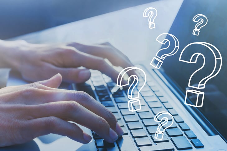 Person typing at computer keyboard with question marks
